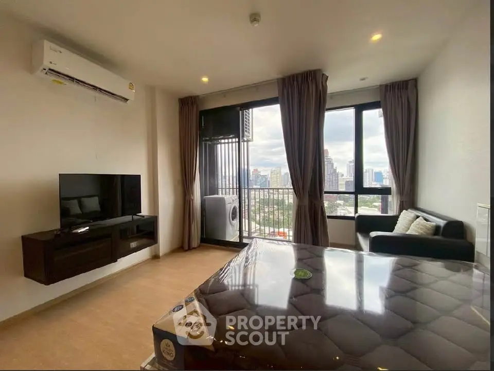Modern living room with city view, featuring sleek furniture and large windows for natural light.