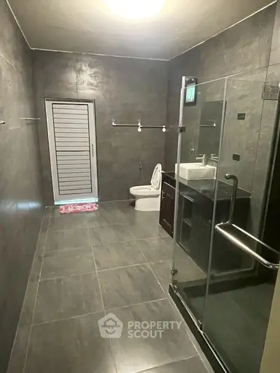 Spacious modern bathroom with sleek tiles and glass shower enclosure.