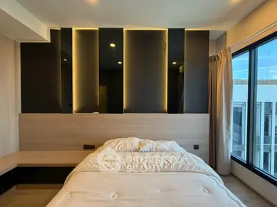Modern bedroom with stylish lighting and large window offering city view