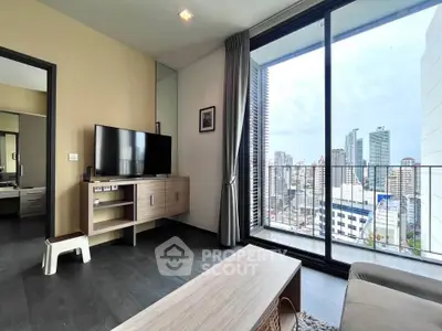 Modern living room with city view, featuring sleek furniture and large glass doors opening to a balcony.