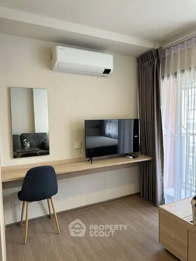 Modern study area with sleek desk, chair, and wall-mounted TV in a bright apartment.
