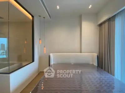 Luxurious bedroom with modern design and large window offering city views.