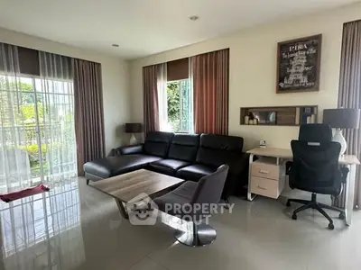 Modern living room with sleek furniture and large windows offering garden views.