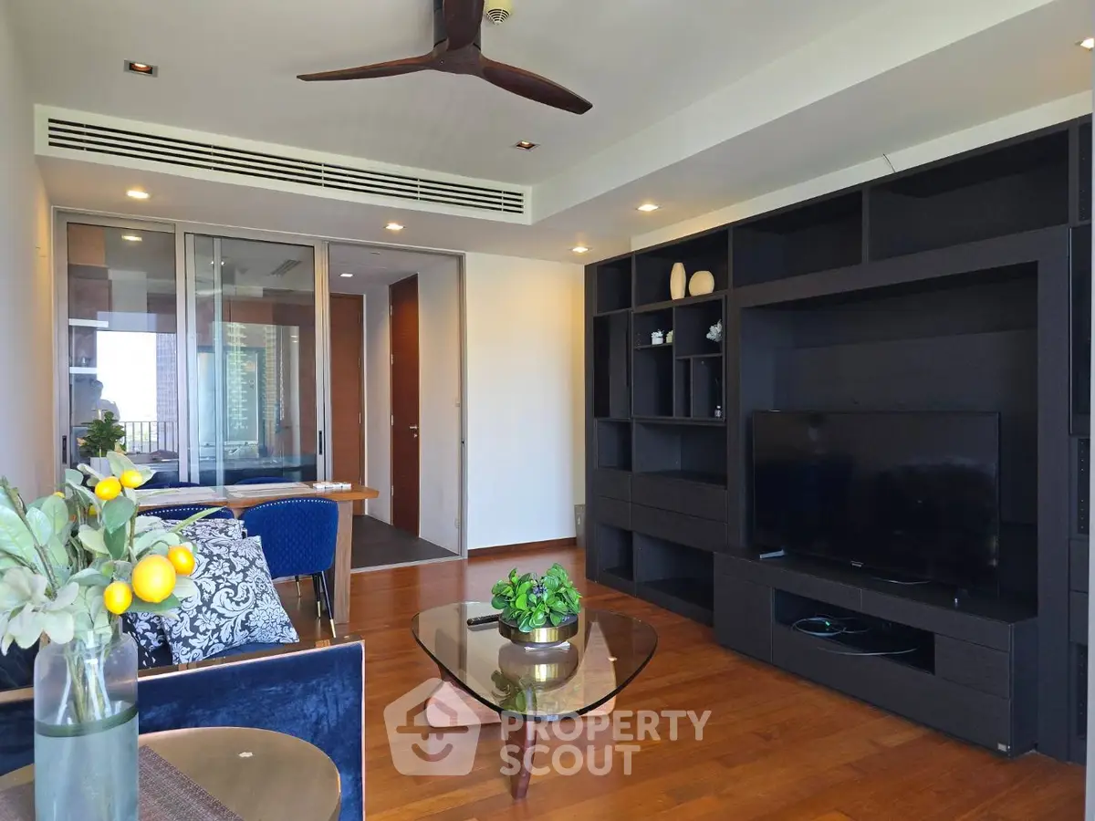 Modern living room with stylish furniture and wooden flooring, featuring a sleek entertainment unit and ceiling fan.