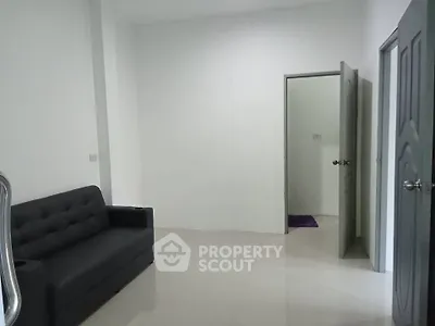 Minimalist living room with gray sofa and open door to adjacent room.