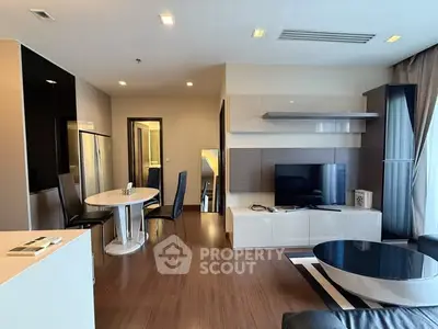 Modern living room with sleek furniture and open layout, featuring a stylish dining area and large TV.