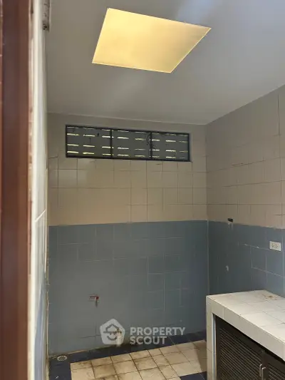 Unfinished bathroom with tiled walls and floor, featuring a small window and plumbing fixtures.
