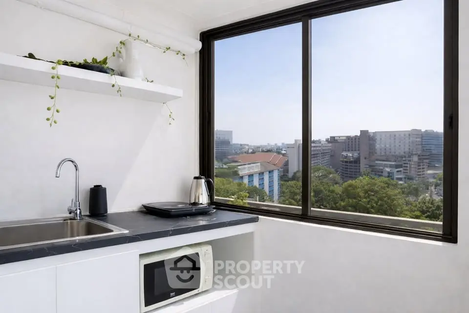 Modern kitchen with city view, featuring sleek countertops and built-in microwave.