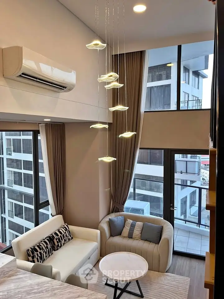 Modern living room with high ceilings, stylish lighting, and large windows offering city views.