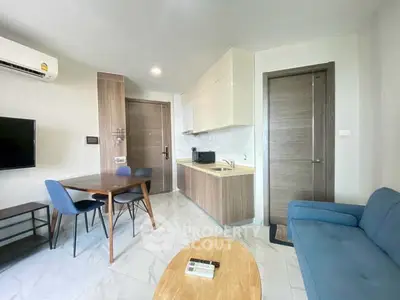 Modern living room with sleek furniture and compact kitchen area.