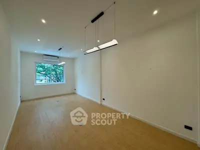 Spacious empty room with large window and modern lighting, ideal for customization.