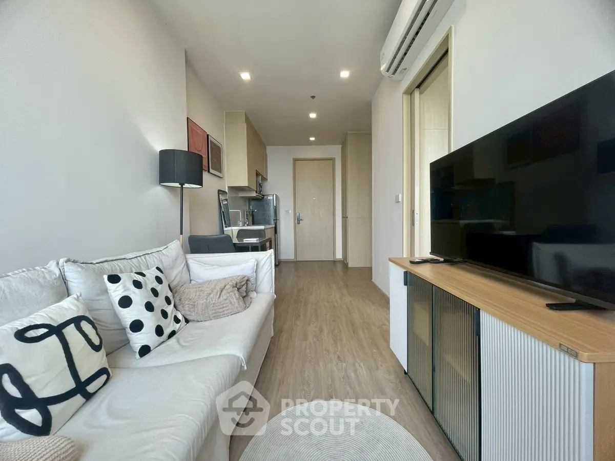 Modern living room with sleek furniture and open kitchen layout in a stylish apartment.