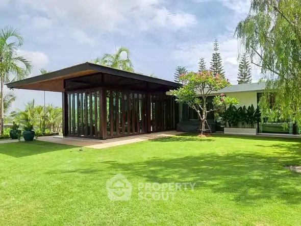 Modern architectural home with lush garden and expansive glass windows.
