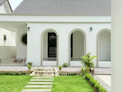 Elegant modern home exterior with arched doorways and lush green lawn