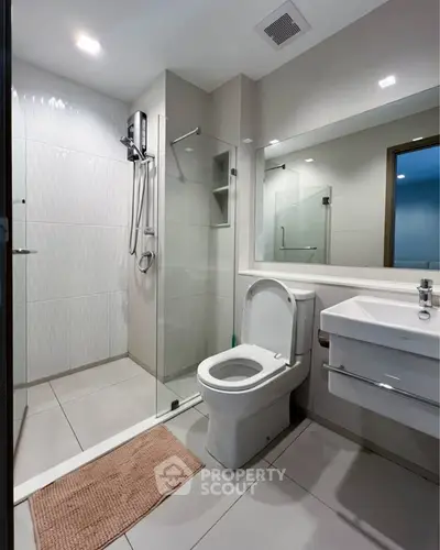 Modern bathroom with glass shower and sleek fixtures in contemporary apartment.