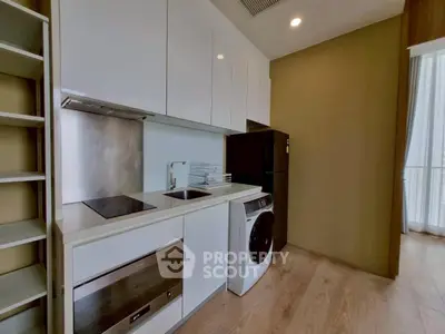 Modern kitchen with sleek cabinetry, built-in oven, and washing machine in a stylish apartment.