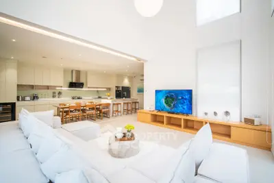 Luxurious open-plan living room with modern kitchen and large TV, perfect for entertaining.