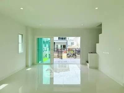 Spacious modern living room with large windows and glossy tile flooring, offering ample natural light and outdoor access.