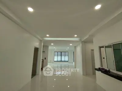 Spacious modern living room with glossy white tiles and recessed lighting.
