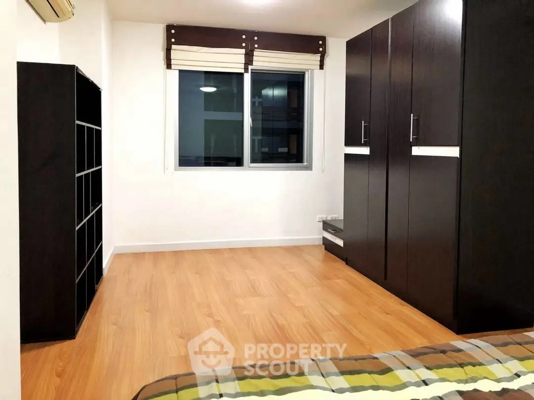 Spacious bedroom with wooden flooring and large wardrobe in modern apartment.