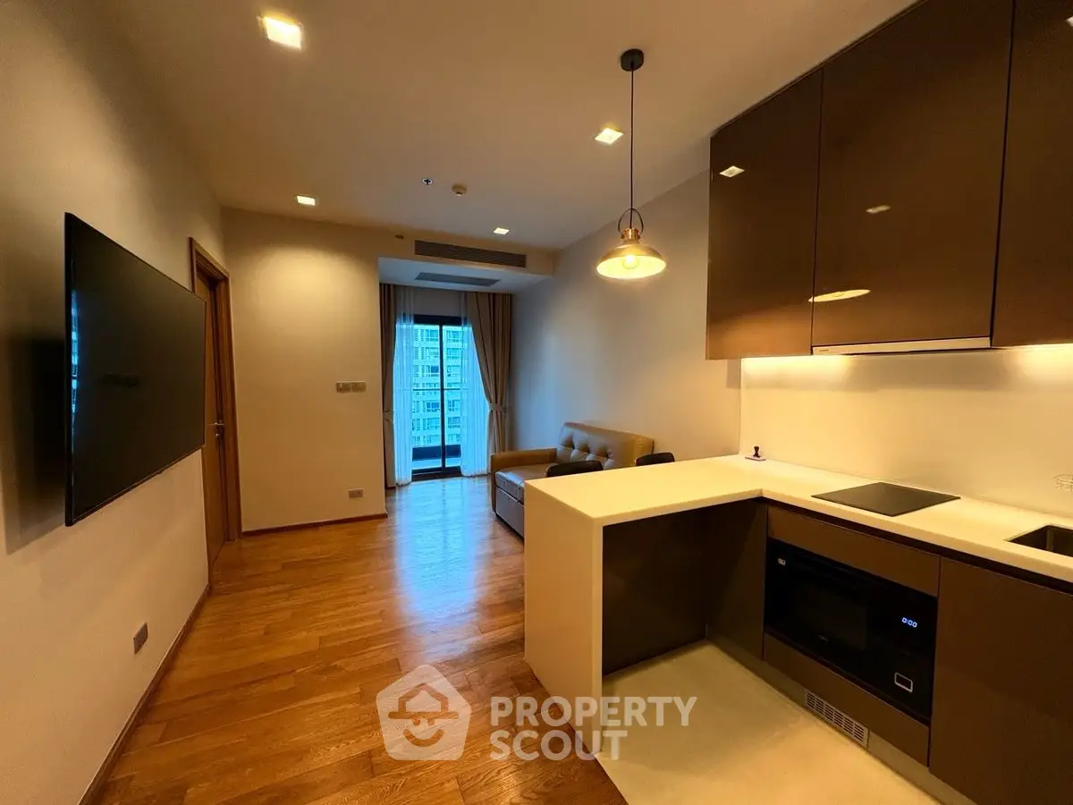 Modern living room with open kitchen and city view, featuring sleek design and hardwood floors.