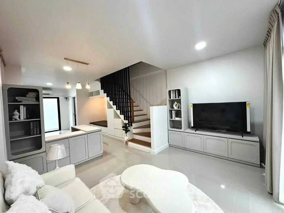 Modern living room with sleek staircase and stylish decor in a contemporary home.