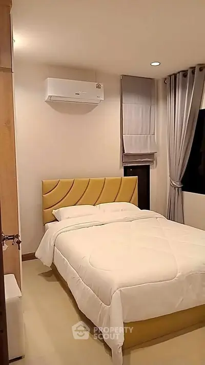 Cozy bedroom with modern decor and air conditioning, featuring a comfortable bed and stylish curtains.