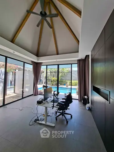 Spacious modern living room with high ceiling and pool view, perfect for luxury living.