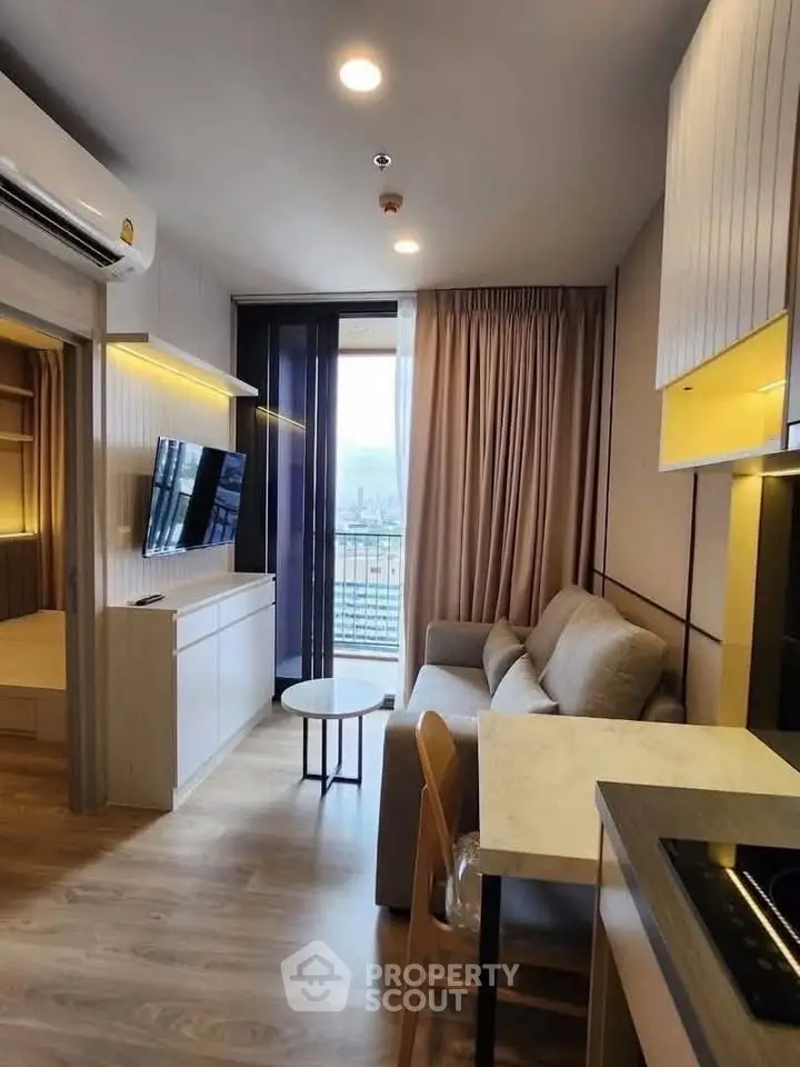 Modern living room with open kitchen and city view, featuring sleek furniture and elegant lighting.