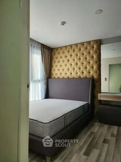 Modern bedroom with stylish tufted headboard and large window for natural light.