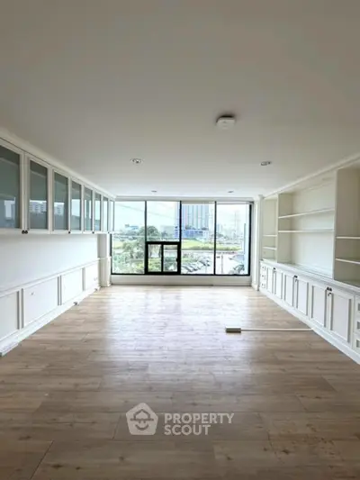 Spacious living room with large windows and built-in shelving, offering a bright and airy atmosphere.
