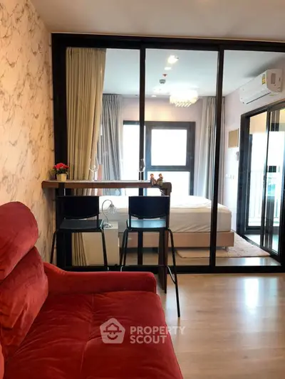 Modern apartment interior with red sofa and glass partitioned bedroom