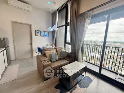 Modern living room with large windows and city view, featuring cozy seating and stylish decor.