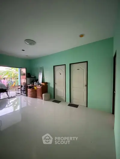 Spacious interior with glossy floors and vibrant green walls, featuring multiple doors and outdoor access.