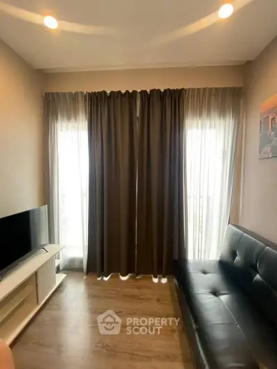 Modern living room with sleek black sofa and large windows with curtains