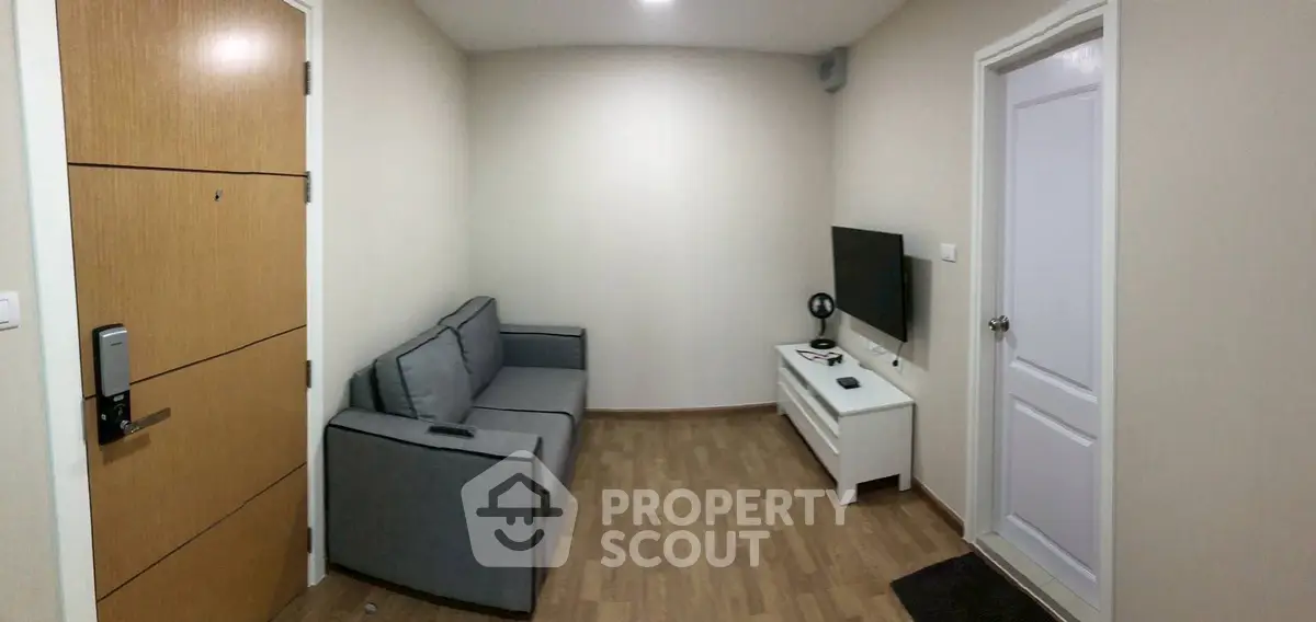 Cozy living room with modern sofa and wall-mounted TV in a compact apartment.