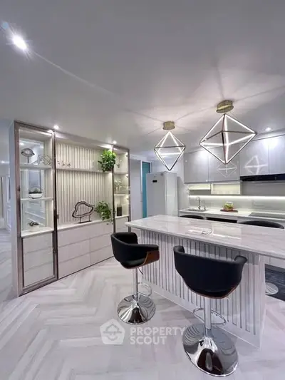 Modern kitchen with sleek design, featuring island seating and geometric pendant lights.