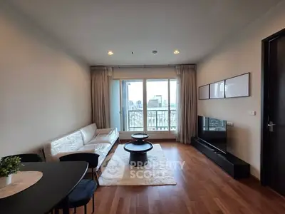 Modern living room with city view, featuring sleek furniture and wooden flooring.