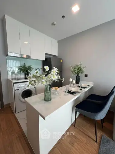 Modern kitchen with open layout featuring sleek white cabinetry, integrated appliances, and a cozy dining area with stylish decor.