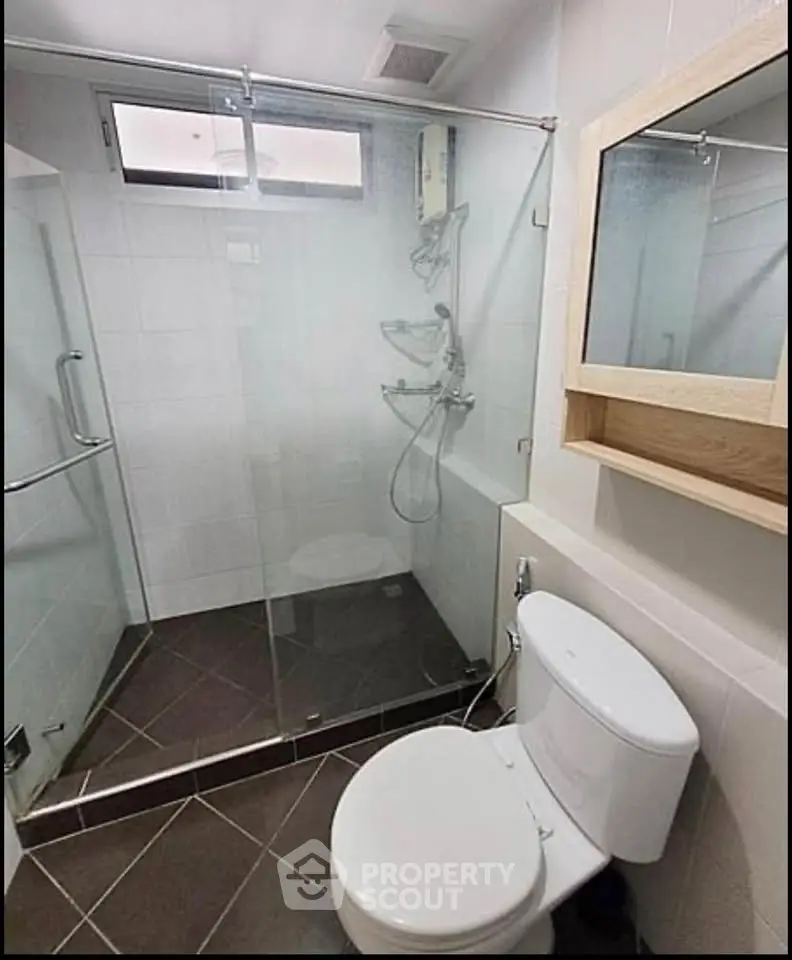 Modern bathroom with glass shower enclosure and sleek fixtures in a contemporary apartment.