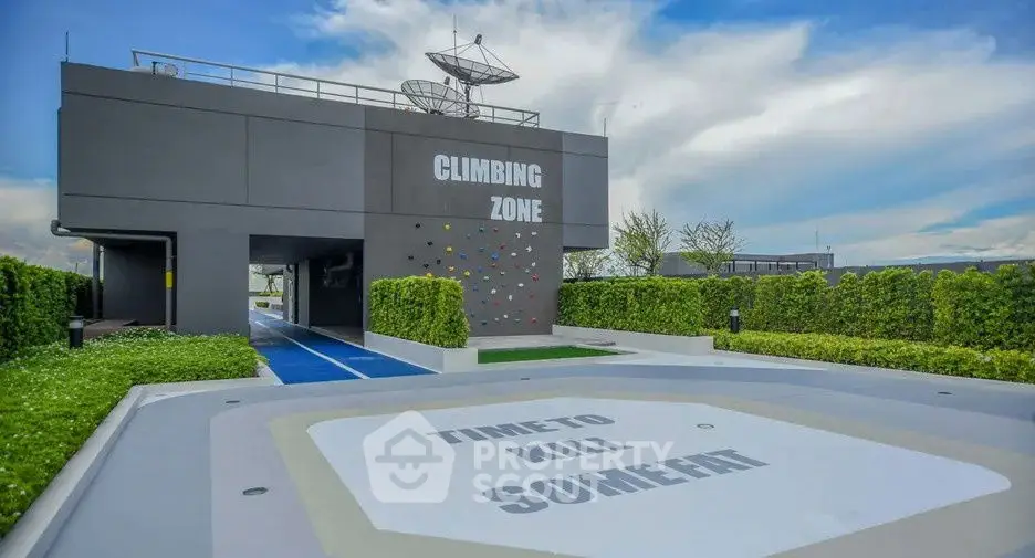 Modern building with climbing wall and rooftop satellite dish in lush green setting.