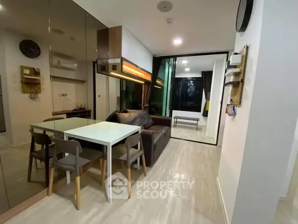 Modern living room with sleek design and open layout, featuring a cozy dining area and stylish furniture.