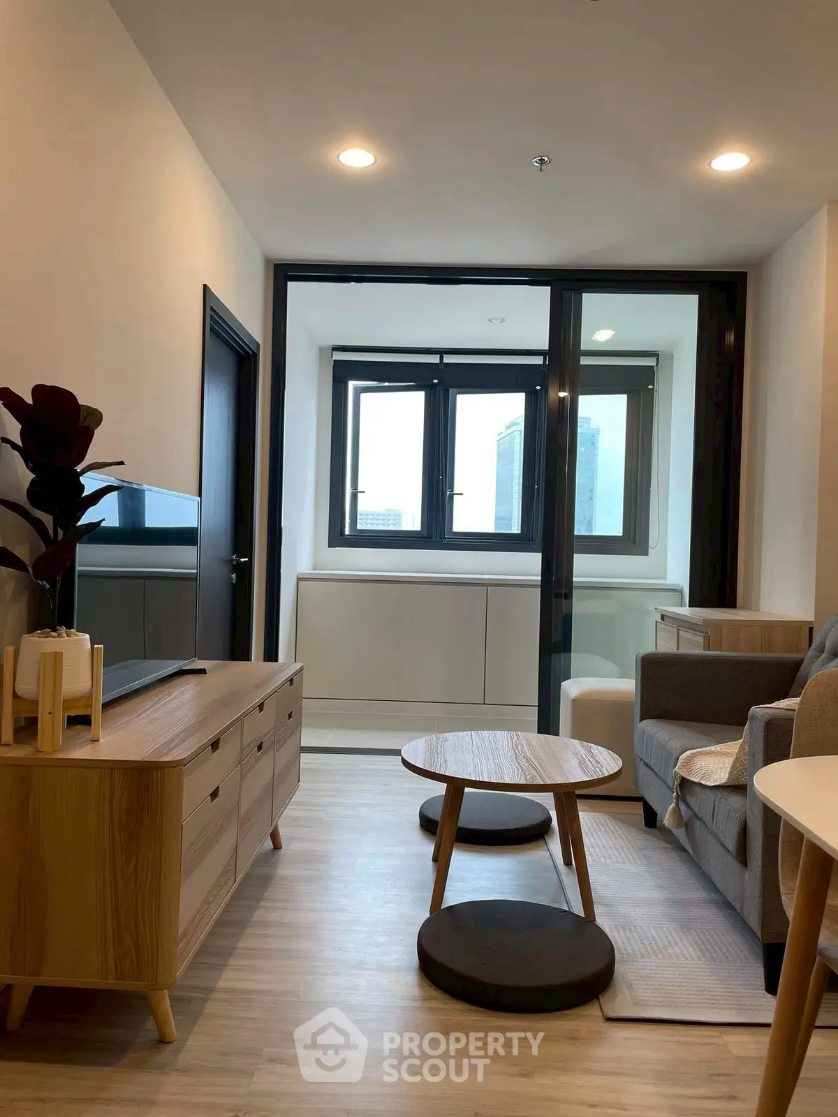 Modern living room with stylish furniture and large windows offering city views.