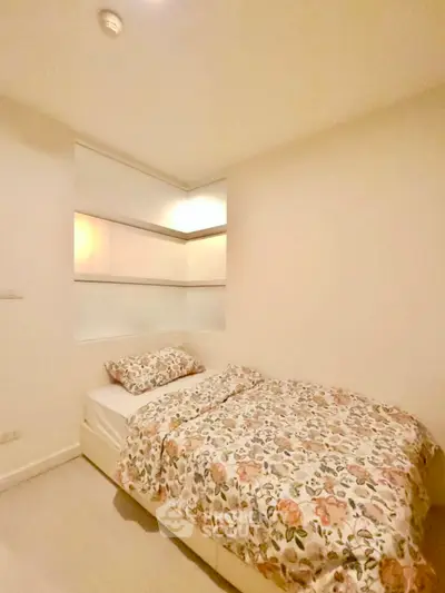 Cozy bedroom with floral bedding and built-in shelves, perfect for a serene retreat.