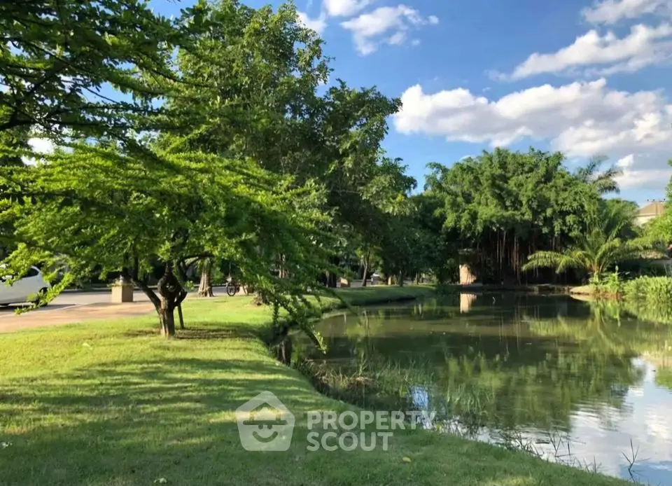 Serene garden view with lush greenery and tranquil pond under blue skies.