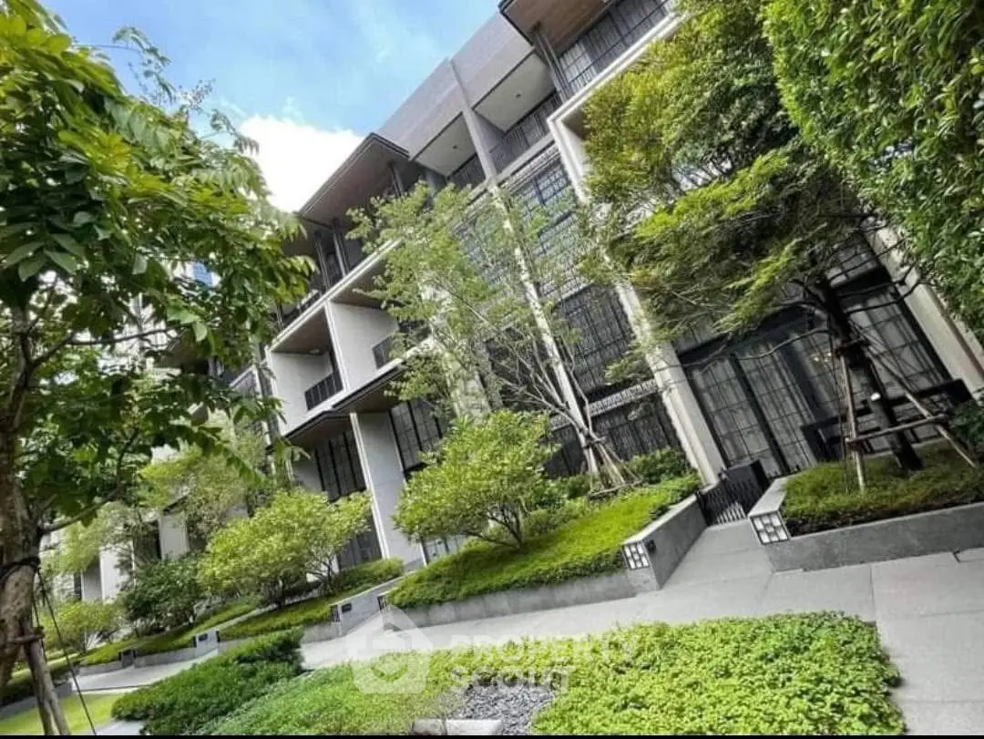 Modern apartment building with lush greenery and sleek architectural design.