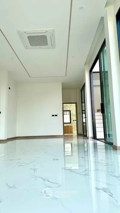 Spacious modern living room with marble flooring and large windows for natural light.
