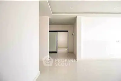 Spacious minimalist interior with sleek white walls and modern sliding doors.