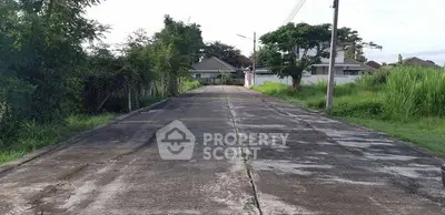 Quiet residential street leading to suburban homes with lush greenery.