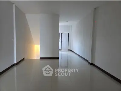 Spacious empty hallway with glossy tiled flooring and white walls